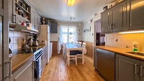 A kitchen with wooden flooring, a dining table with chairs, and stainless steel appliances.