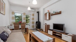 En hyggelig stue med sofa, fjernsyn, pejs og spiseplads med bord og stole.