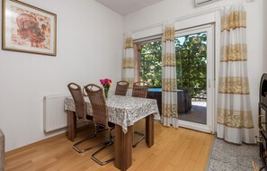 A dining area with a table, wicker chairs, and a vase of flowers.