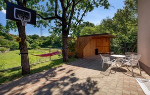 A basketball hoop attached to a tree, a hammock, outdoor seating, and a wooden structure.