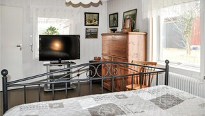 A bedroom with a bed, a TV, a wooden cabinet, and a window with a view of the outside. - 3 bedroom pet friendly home in Säffle (Säffle)