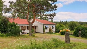 A small, single-story house with a red-tiled roof, surrounded by a lush garden and a large tree. - 3 bedroom pet friendly home in Säffle (Säffle)