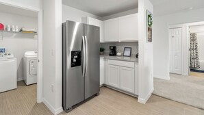 Cocina moderna con electrodomésticos de acero inoxidable, armarios blancos y dispensador de agua integrado.
