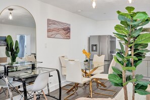 A modern dining area with a glass table, white chairs, and a minimalist design.