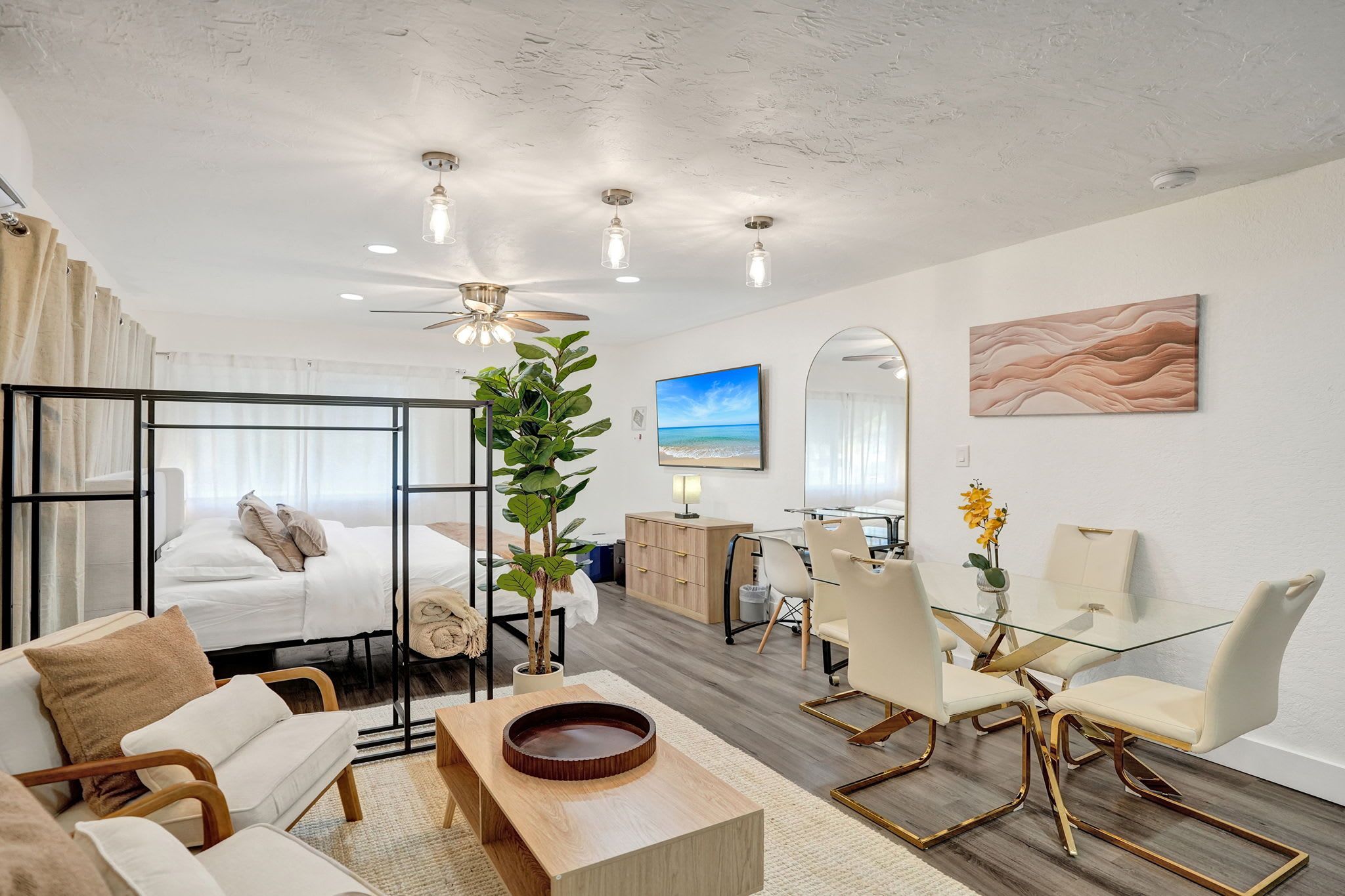 Une chambre d’hôtel moderne équipée d’un lit, d’un coin salon, d’une table à manger et offrant une vue sur la plage.
