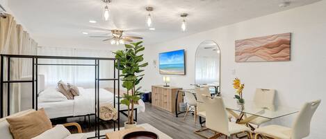 Une chambre d’hôtel moderne équipée d’un lit, d’un coin salon, d’une table à manger et offrant une vue sur la plage.
