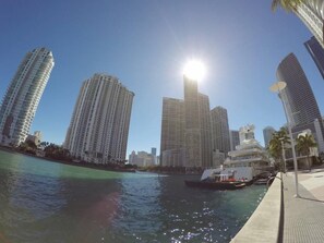 Un paisaje urbano frente al agua con rascacielos, un barco amarrado en el muelle y cielo despejado.