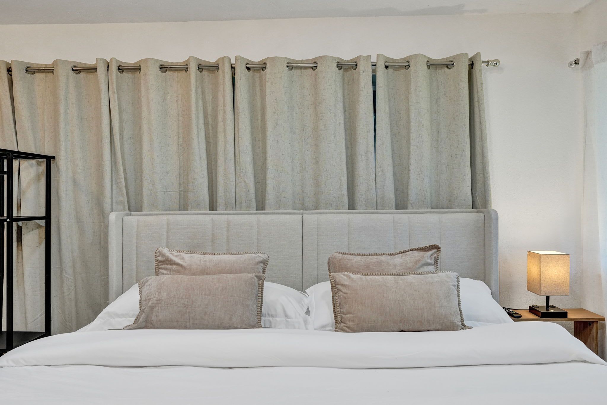 A neatly made bed with two pillows, a headboard, and a nightstand with a lamp.