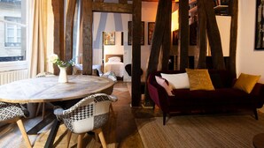 A cozy room with a round wooden table, a red sofa, and a bed with a white headboard. - High Stay Saint Germain de Pres Paris 6 (Paris)