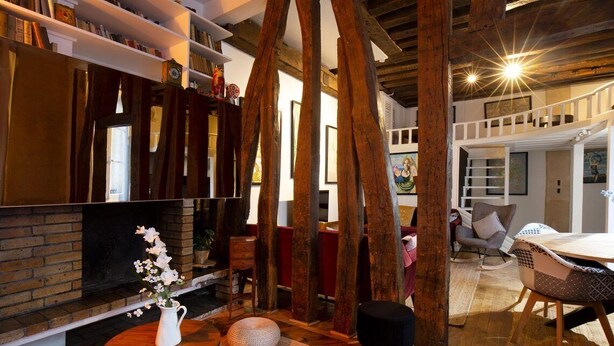A cozy living room with a fireplace, wooden beams, and a dining area with a table and chairs. - High Stay Saint Germain de Pres Paris 6 (Paris)