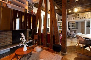 A cozy living room with a fireplace, wooden beams, and a dining area with a table and chairs. - High Stay Saint Germain de Pres Paris 6 (Paris)
