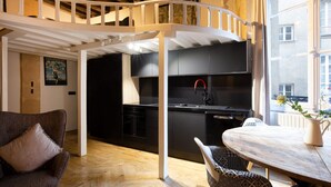 A modern kitchen with black cabinets, a white ceiling, and a wooden dining table with patterned chairs. - High Stay Saint Germain de Pres Paris 6 (Paris)