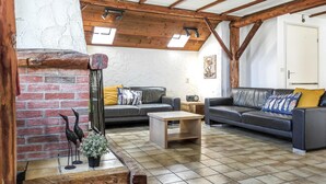 A rustic living room with exposed wooden beams, a brick wall, two leather sofas with cushions, a small wooden table, and a decorative bird sculpture. - Amazing home in Vledder with WiFi (Vledder)