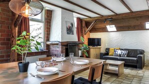 A dining area with a wooden table set for four, a brick wall, and a fireplace. - Amazing home in Vledder with WiFi (Vledder)