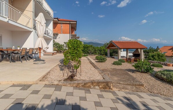 Un patio con zona de comedor, mobiliario exterior y área de barbacoa.