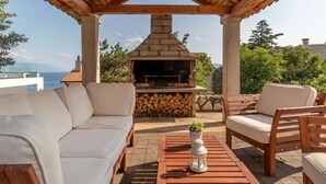 An outdoor seating area with a stone fireplace, a sofa, and a table with a lantern.