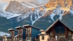 Un albergue de montaña con varias cabañas, cada una con amplias ventanas y revestimiento de madera.