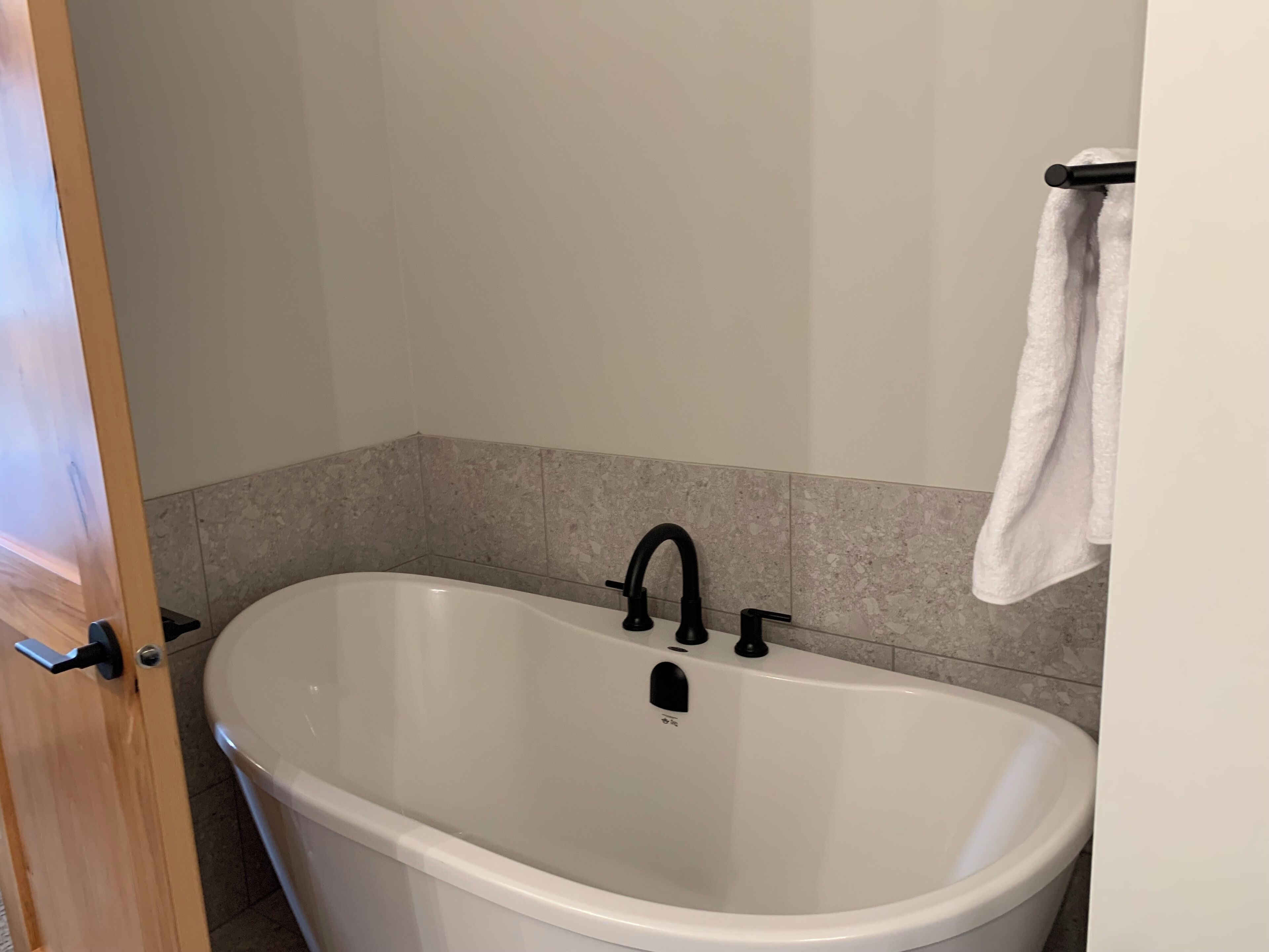 A bathroom with a freestanding bathtub, a towel rack, and a door.