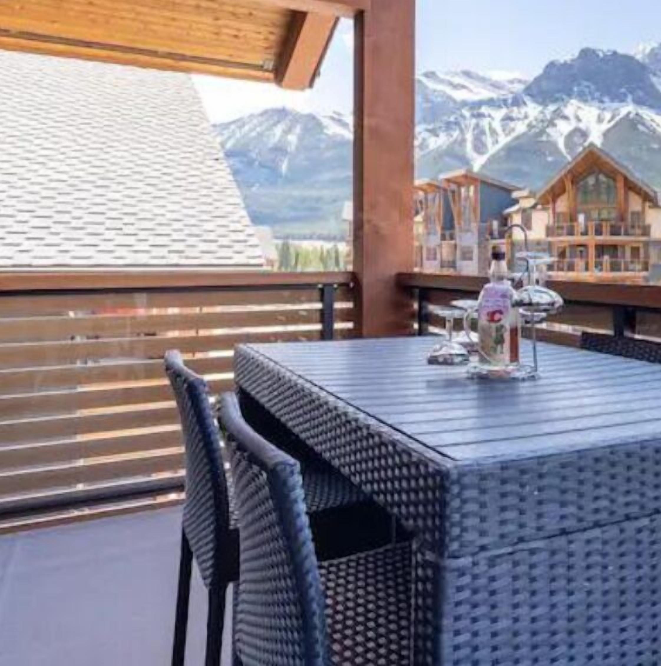 A balcony with a table and chairs, overlooking a mountain landscape.