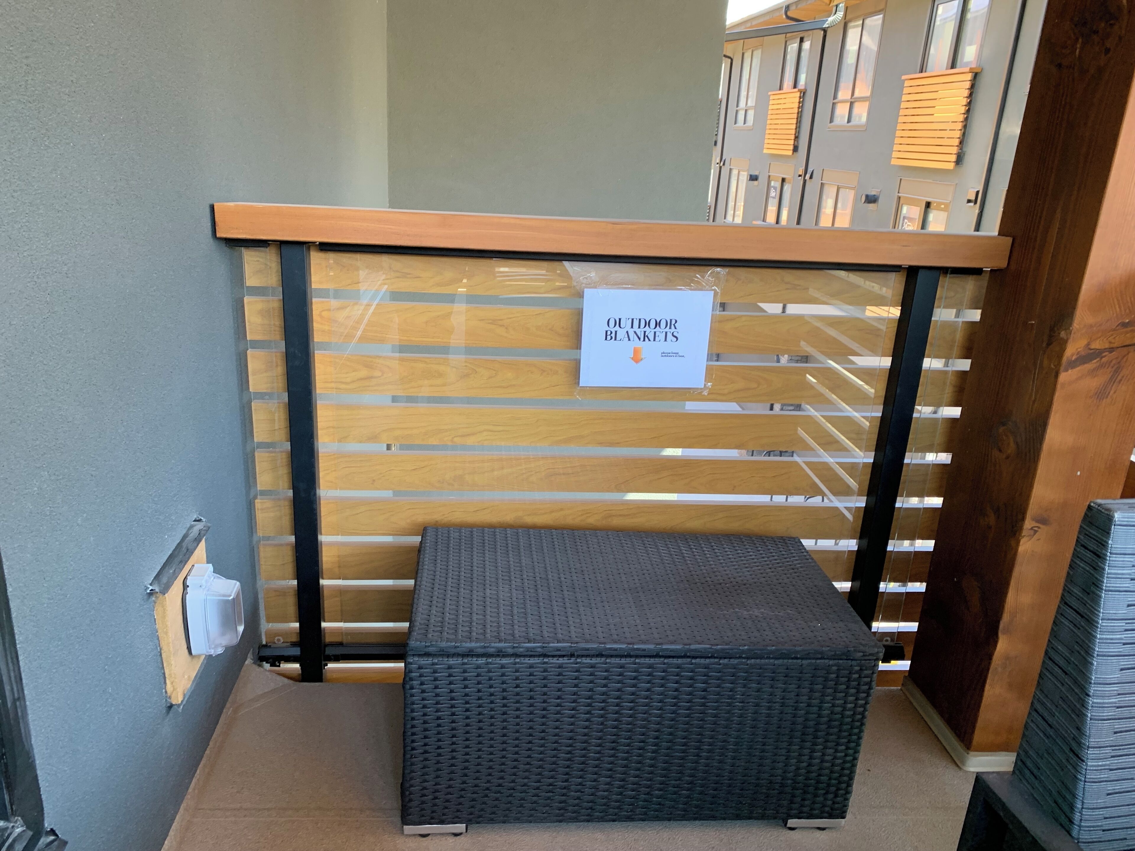 A section of a hotel with a wooden bench, a sign indicating outdoor blankets, and a wall with a window.