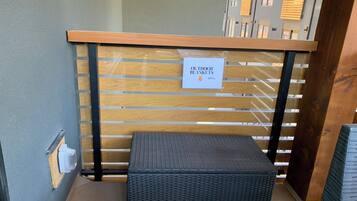 A section of a hotel with a wooden bench, a sign indicating outdoor blankets, and a wall with a window.