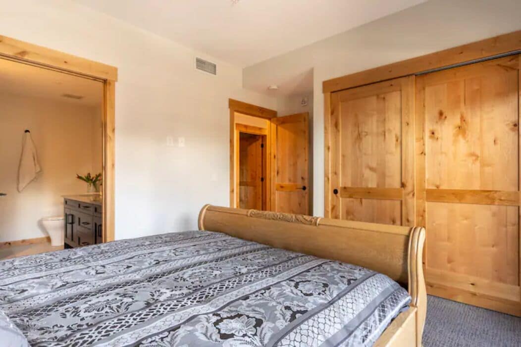Un dormitorio con cama, armario de madera y un escritorio pequeño con una planta.