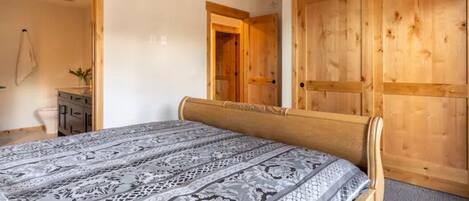 Un dormitorio con cama, armario de madera y un escritorio pequeño con una planta.