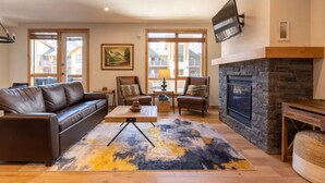 Una sala de estar amplia con chimenea, sofá de cuero y un gran ventanal.