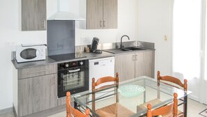 A compact kitchen with a microwave, stove, oven, and dishwasher. There is a glass dining table with chairs. - 2 bedroom awesome home in Langon (Langon)