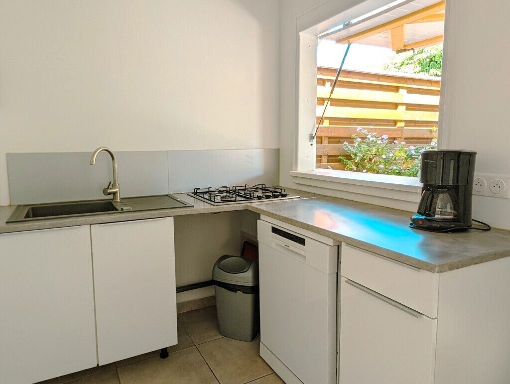Una cocina compacta con un lavamanos, estufa y ventana con vistas a un jardín.