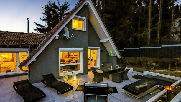 A modern house with a patio area featuring outdoor furniture, a grill, and a view of the interior. - 2 bedroom beautiful home in Ulrichstein (Ulrichstein)
