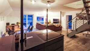 A modern kitchen with a central island, a dining area with a table and chairs, a living room with a sofa and a TV, and a staircase leading to an upper level. - 2 bedroom beautiful home in Ulrichstein (Ulrichstein)