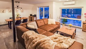 A living room with a brown sectional sofa, a coffee table, and a dining area with a wooden table and chairs. - 2 bedroom beautiful home in Ulrichstein (Ulrichstein)