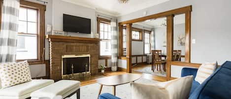 A living room with a fireplace, a television, and a large mirror.