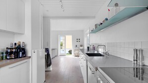 Una cocina moderna con armarios blancos, un lavamanos de acero inoxidable y una variedad de botellas de vino sobre la encimera.