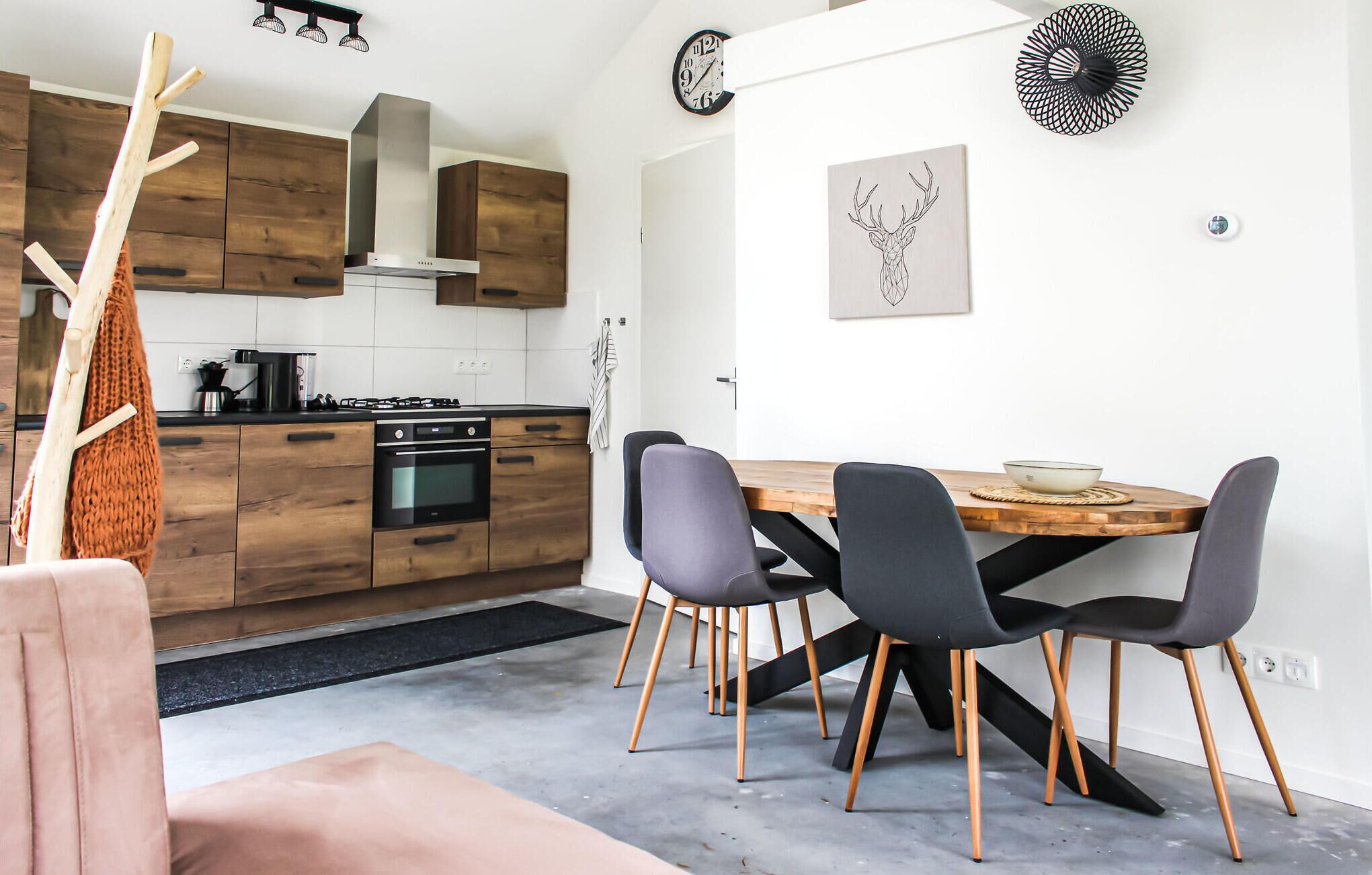 Eine moderne Küche mit Holzschränken, einem Herd und einem Essbereich mit einem Holztisch und vier Stühlen.