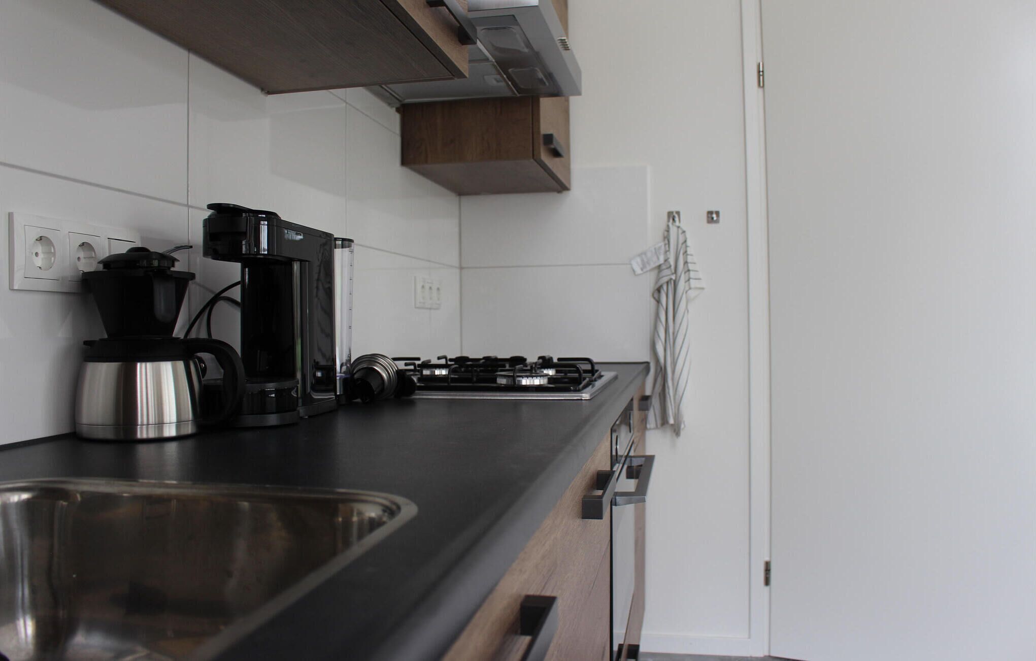 A kitchen with a stainless steel sink, a coffee maker, and a stove.