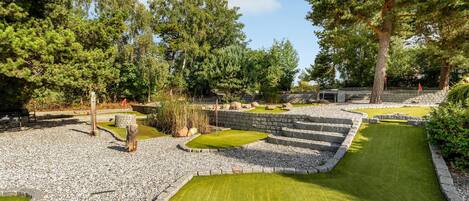 A miniature golf course with stone walls, green grass, and trees.