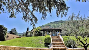 A stone staircase leading to a house with a tiled roof, surrounded by well-maintained grass and shrubs. - Nice home in Condorcet (Condorcet)