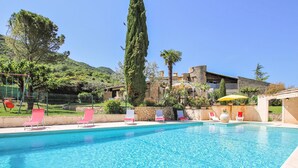 A swimming pool with lounge chairs and a stone building in the background. - Nice home in Condorcet (Condorcet)