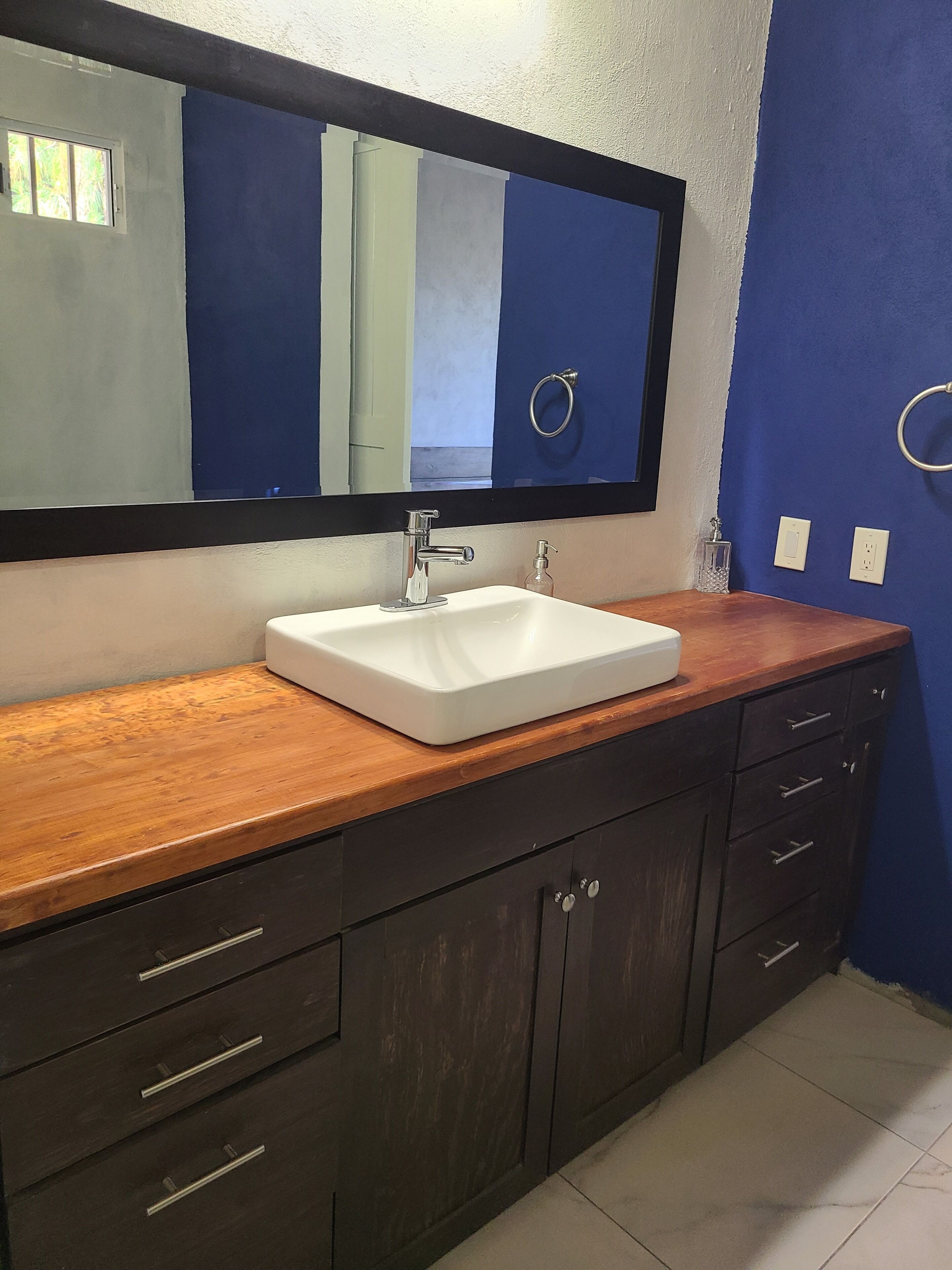 A bathroom with a white sink, dark wooden vanity, and a large mirror.