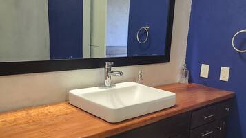 A bathroom with a white sink, dark wooden vanity, and a large mirror.
