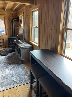 Ein gemütliches Blockhaus mit Holzvertäfelungen, einem großen Fenster, einem Kamin und einem Tisch.