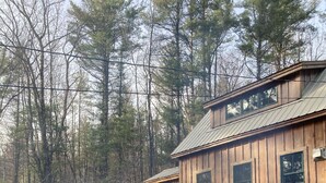 Eine Holzhütte mit zwei Holzstühlen und einem Feuerkorb im Vordergrund.