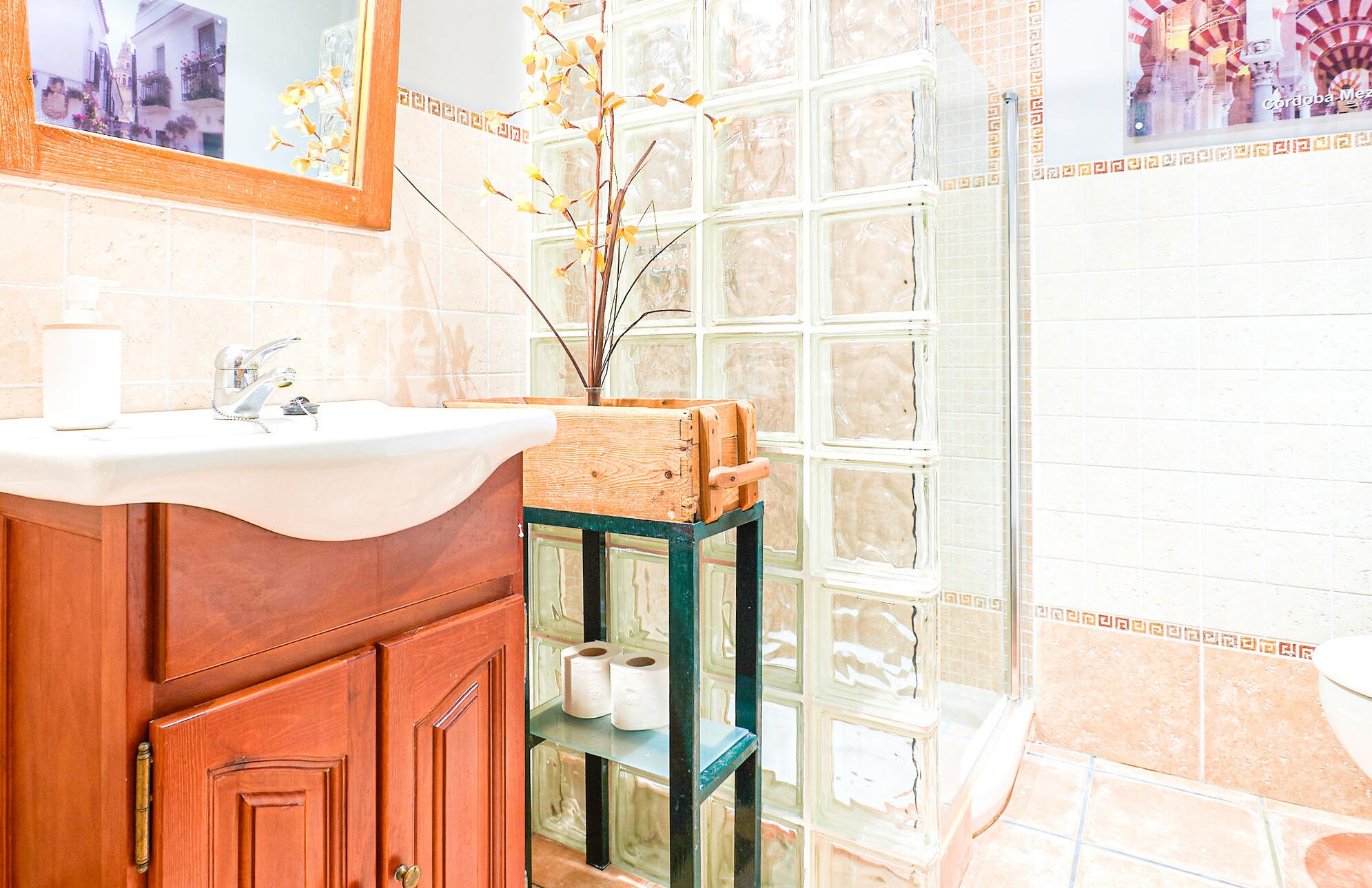 A bathroom with a wooden vanity, a white sink, and a glass shower enclosure.