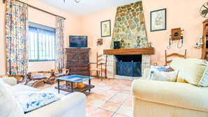 A living room with a fireplace, a television, and a stone wall. - Nice home in Villafranca de Cordoba (Villafranca de Cordoba)