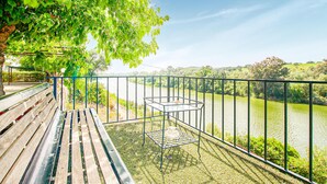 A wooden bench and a metal table with a bowl on a grassy area overlooking a river. - Nice home in Villafranca de Cordoba (Villafranca de Cordoba)