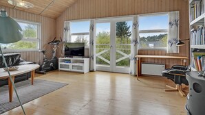 Ett mysigt rum med ett löpband, en tv och ett skrivbord med en dator.