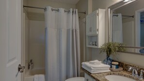 A bathroom with a shower curtain, a sink with a vase of flowers, and a mirror. - Cozy Cottage located in an Apple Orchard - 5 mins from Downtown Hendersonville (Hendersonville)