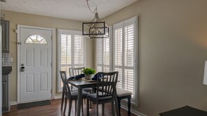 A dining area with a table and chairs, a hanging light fixture, and a door with a window.